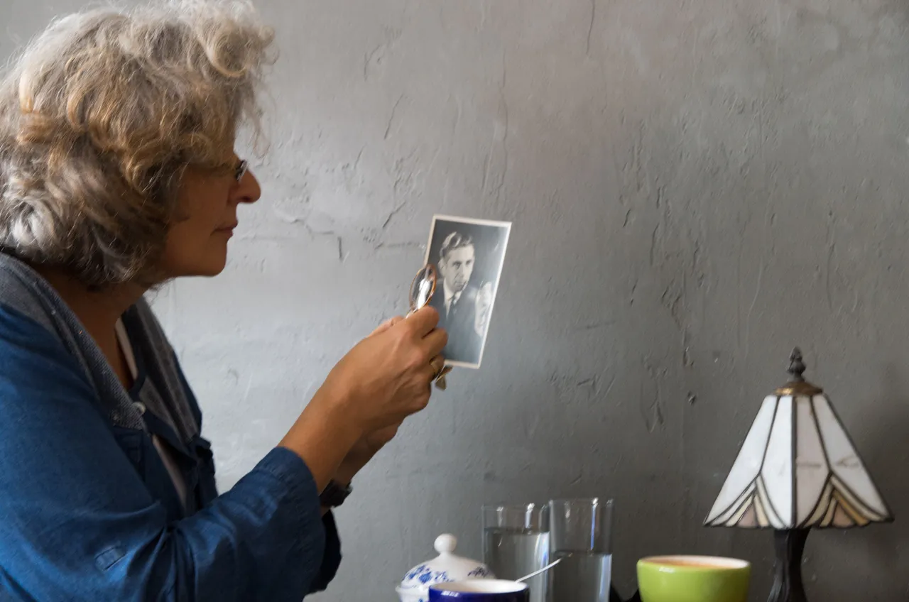Eine ältere Frau hält eine alte Fotografie in den Händen und betrachtet sie.